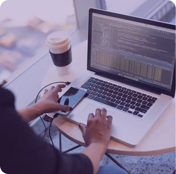 A group of people sitting around a table working on a laptop.