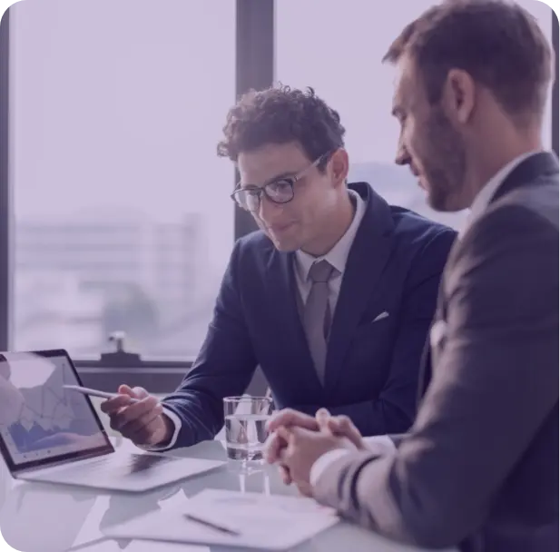 A group of people sitting around a table working on a laptop.