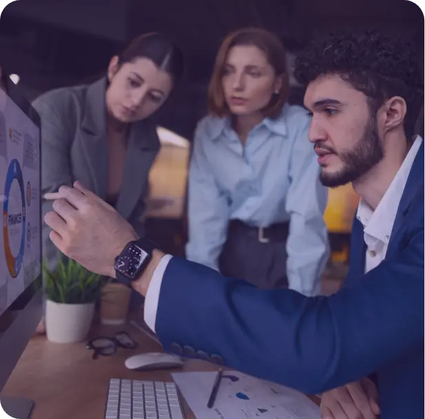 A group of people sitting around a table working on a laptop.